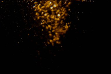 Soyut bulanık altın bokeh ışıkları koyu bir arkaplan karşısında dramatik ve şenlikli bir atmosfer yaratır.