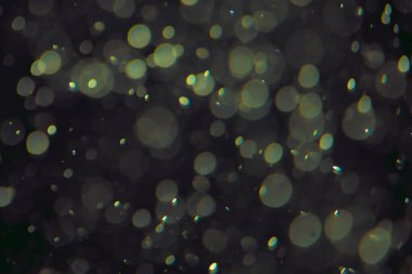 Koyu bir arkaplanda farklı boyut ve renklerde odaklanmış bokeh ışıkları.