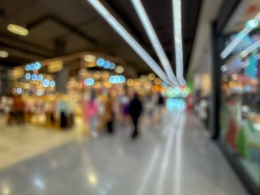 Hareketli bir alışveriş merkezinin bulanık görüntüsü modern bir perakende satış ortamının canlı atmosferini yakalıyor. İnsanlar yürürken, alışveriş yaparken ve eğlenirken görülürler.