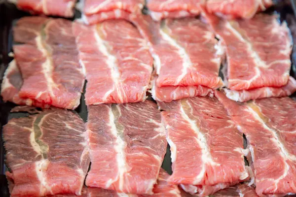 Çiğ et dilimlerinin karmaşık mermerlerini gösteren yakın plan bir fotoğraf. Parlak kırmızı renkler, beyaz yağ çizgileriyle çok güzel tezat oluşturuyor.