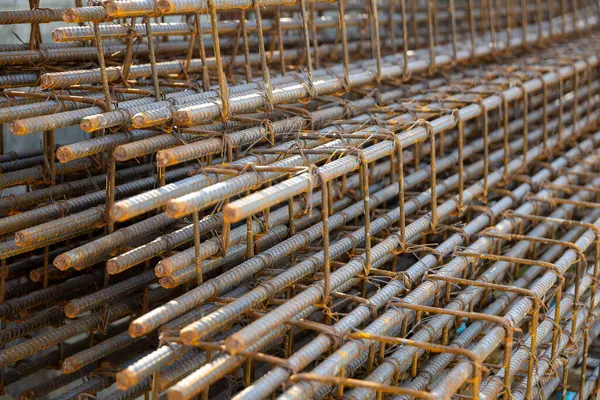 İnşaatta beton takviyesi için kullanılan çelik inşaat ızgarasına yakın çekim. Dayanıklılık için gerekli olan paslı çubuk deseni gösteriliyor.