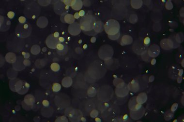 Koyu bir arkaplanda farklı boyut ve renklerde odaklanmış bokeh ışıkları.