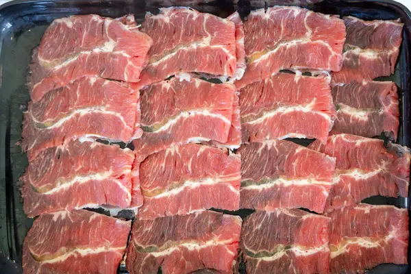 Çiğ et dilimlerinin karmaşık mermerlerini gösteren yakın plan bir fotoğraf. Parlak kırmızı renkler, beyaz yağ çizgileriyle çok güzel tezat oluşturuyor.