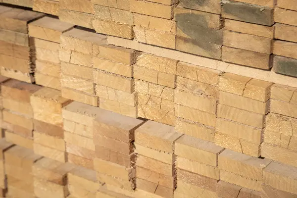 Kereste deposunda istiflenmiş ahşap kalaslar, çeşitli gölgeler ve dokular, düzenli bir şekilde düzenlenmiş..