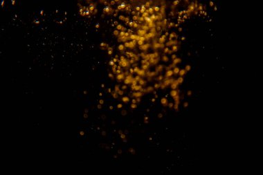 Soyut bulanık altın bokeh ışıkları koyu bir arkaplan karşısında dramatik ve şenlikli bir atmosfer yaratır.