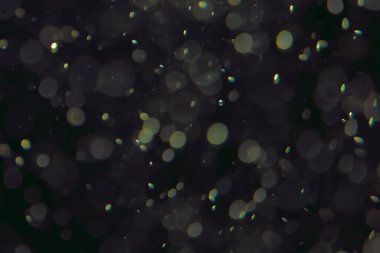 Koyu bir arkaplanda farklı boyut ve renklerde odaklanmış bokeh ışıkları.