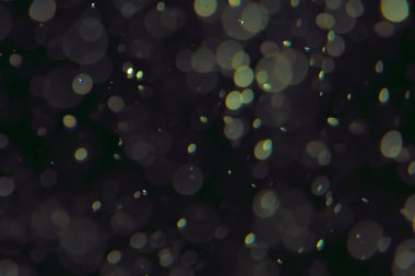 Koyu bir arkaplanda farklı boyut ve renklerde odaklanmış bokeh ışıkları.