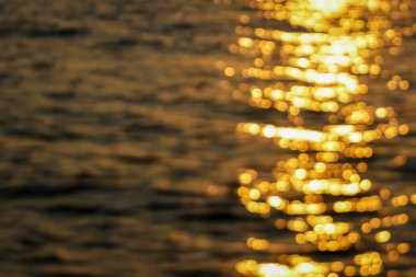 Bulanık bokeh etkisi soyut görüntü güneş ışığının su üzerindeki altın yansımalarını yakalıyor, rüya gibi bir görüntü yaratıyor.