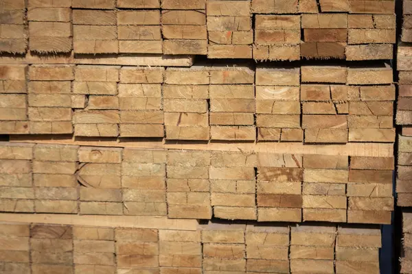 Kereste deposunda istiflenmiş ahşap kalaslar, çeşitli gölgeler ve dokular, düzenli bir şekilde düzenlenmiş..