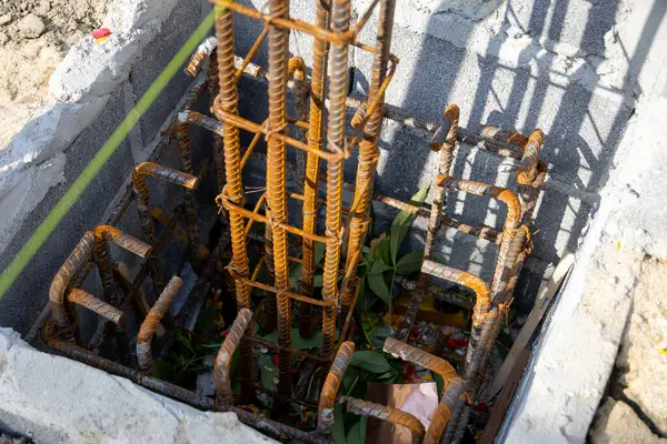 İnşaat için hazırlanmış çelik bir demir kafesi olan beton bir temele yakın çekim. İnşaat desteğinin ilk aşamasını gösterir