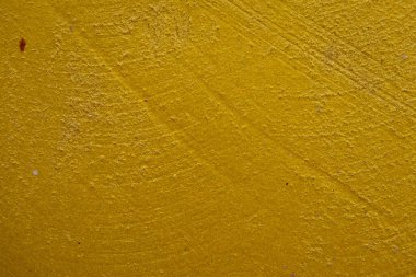 Kalıplı sarı beton yüzeyin yakın plan çekimi. Kaba ve biraz pürüzlü doku ve altın sarısındaki ince varyasyonlar, görsel olarak ilginç bir zemin oluşturur. Bazı ince yatay çizgiler görünür..