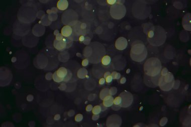 Koyu bir arkaplanda farklı boyut ve renklerde odaklanmış bokeh ışıkları.