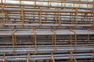İnşaatta beton takviyesi için kullanılan çelik inşaat ızgarasına yakın çekim. Dayanıklılık için gerekli olan paslı çubuk deseni gösteriliyor.