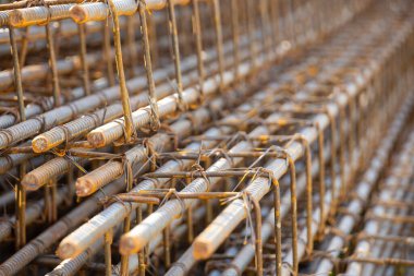 İnşaatta beton takviyesi için kullanılan çelik inşaat ızgarasına yakın çekim. Dayanıklılık için gerekli olan paslı çubuk deseni gösteriliyor.