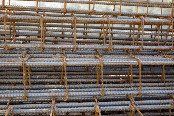 İnşaatta beton takviyesi için kullanılan çelik inşaat ızgarasına yakın çekim. Dayanıklılık için gerekli olan paslı çubuk deseni gösteriliyor.