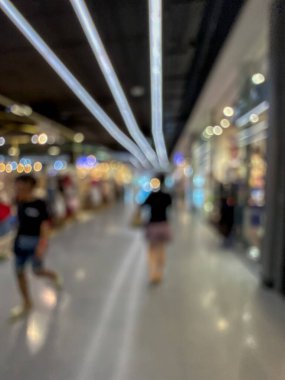 Hareketli bir alışveriş merkezinin bulanık görüntüsü modern bir perakende satış ortamının canlı atmosferini yakalıyor. İnsanlar yürürken, alışveriş yaparken ve eğlenirken görülürler.