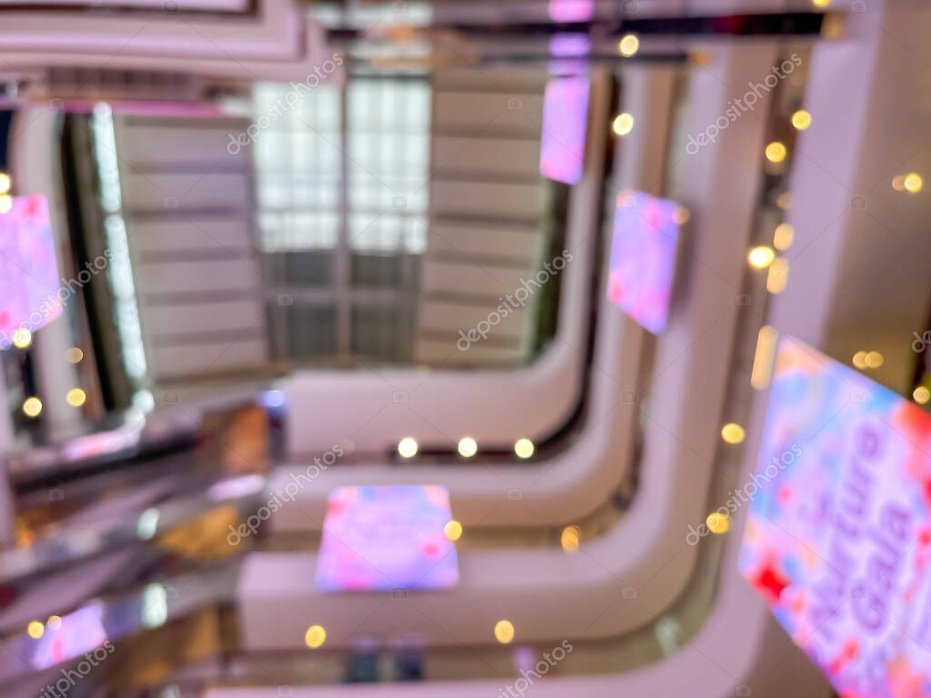 Blurred image of a bustling shopping mall, capturing the vibrant atmosphere of a modern retail environment. People are seen shopping