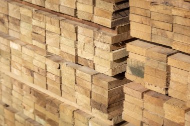 Kereste deposunda istiflenmiş ahşap kalaslar, çeşitli gölgeler ve dokular, düzenli bir şekilde düzenlenmiş..