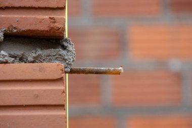 İnşaat alanının yakın çekimi tuğla bir duvarın köşesini gösteriyor. Demiri açık ve taze havan topu var. Odak noktamız inşaat süreci..