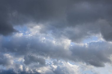 Gri ve koyu renkli bulutlarla dolu geniş bir gökyüzü görüntüsü yaklaşan bir fırtına ya da karamsar bir atmosferi işaret ediyor..
