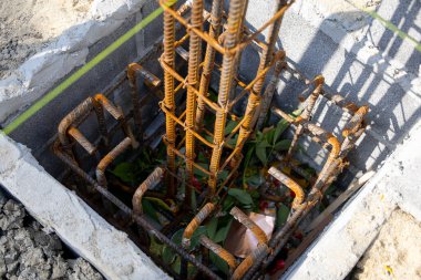 İnşaat için hazırlanmış çelik bir demir kafesi olan beton bir temele yakın çekim. İnşaat desteğinin ilk aşamasını gösterir