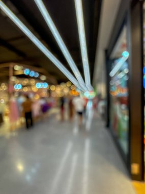 Hareketli bir alışveriş merkezinin bulanık görüntüsü modern bir perakende satış ortamının canlı atmosferini yakalıyor. İnsanlar yürürken, alışveriş yaparken ve eğlenirken görülürler.