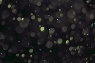 Koyu bir arkaplanda farklı boyut ve renklerde odaklanmış bokeh ışıkları.