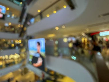 Hareketli bir alışveriş merkezinin bulanık görüntüsü modern bir perakende satış ortamının canlı atmosferini yakalıyor. İnsanlar alışveriş yaparken görülüyor.