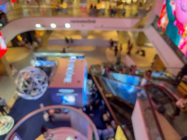 Hareketli bir alışveriş merkezinin bulanık görüntüsü modern bir perakende satış ortamının canlı atmosferini yakalıyor. İnsanlar alışveriş yaparken görülüyor.