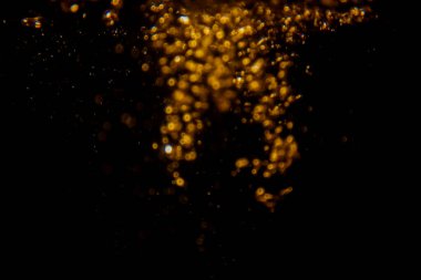 Soyut bulanık altın bokeh ışıkları koyu bir arkaplan karşısında dramatik ve şenlikli bir atmosfer yaratır.