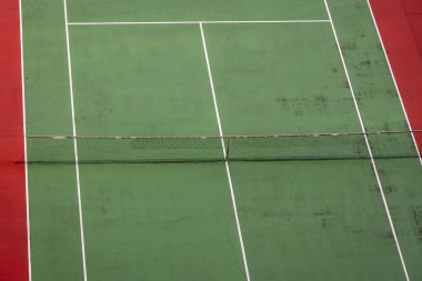 Canlı kırmızı ve yeşil açık hava tenis kortunun beyaz çizgileri, spor, dinlenme ve kentsel manzara temaları için ideal bir görüntüsü.
