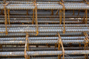 İnşaatta beton takviyesi için kullanılan çelik inşaat ızgarasına yakın çekim. Dayanıklılık için gerekli olan paslı çubuk deseni gösteriliyor.