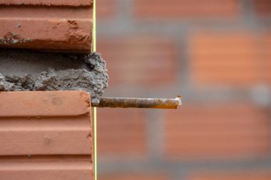 İnşaat alanının yakın çekimi tuğla bir duvarın köşesini gösteriyor. Demiri açık ve taze havan topu var. Odak noktamız inşaat süreci..