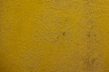 Kalıplı sarı beton yüzeyin yakın plan çekimi. Kaba ve biraz pürüzlü doku ve altın sarısındaki ince varyasyonlar, görsel olarak ilginç bir zemin oluşturur. Bazı ince yatay çizgiler görünür..