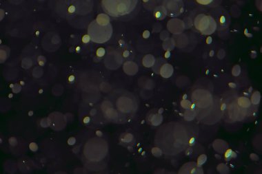 Koyu bir arkaplanda farklı boyut ve renklerde odaklanmış bokeh ışıkları.