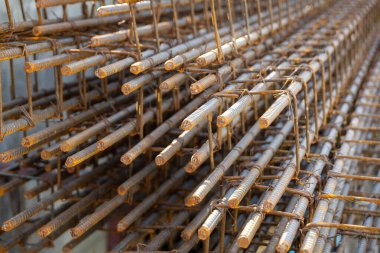 İnşaatta beton takviyesi için kullanılan çelik inşaat ızgarasına yakın çekim. Dayanıklılık için gerekli olan paslı çubuk deseni gösteriliyor.