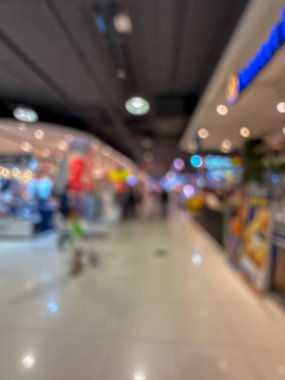 Hareketli bir alışveriş merkezinin bulanık görüntüsü modern bir perakende satış ortamının canlı atmosferini yakalıyor. İnsanlar yürürken, alışveriş yaparken ve eğlenirken görülürler.