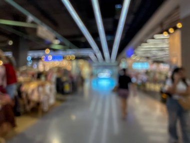 Hareketli bir alışveriş merkezinin bulanık görüntüsü modern bir perakende satış ortamının canlı atmosferini yakalıyor. İnsanlar yürürken, alışveriş yaparken ve eğlenirken görülürler.