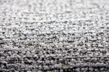 Açık gri ve koyu renkli ipliklerin karışımı sıkıca dokunmuş bir kumaşın yakın çekim görüntüsü ince desenli bir desen oluşturur..