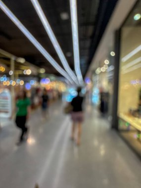 Hareketli bir alışveriş merkezinin bulanık görüntüsü modern bir perakende satış ortamının canlı atmosferini yakalıyor. İnsanlar yürürken, alışveriş yaparken ve eğlenirken görülürler.