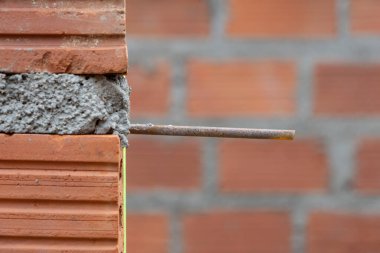 İnşaat alanının yakın çekimi tuğla bir duvarın köşesini gösteriyor. Demiri açık ve taze havan topu var. Odak noktamız inşaat süreci..