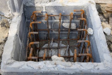İnşaat için hazırlanmış çelik bir demir kafesi olan beton bir temele yakın çekim. İnşaat desteğinin ilk aşamasını gösterir