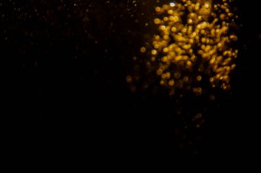 Soyut bulanık altın bokeh ışıkları koyu bir arkaplan karşısında dramatik ve şenlikli bir atmosfer yaratır.