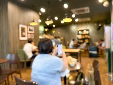 Müşterilerle dolu bir kafenin bulanık görüntüsü. Sosyal ortam için soyut ve atmosferik bir görünüm oluşturur