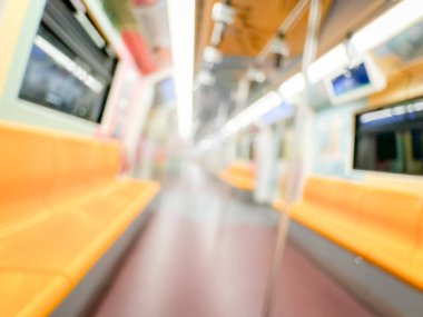 Parlak sarı koltukları ve paslanmaz çelik direkleriyle metro içi boş bir metro manzarası. Modern tren vagonu iyi ışıklandırılmış, üst kulpları ve pürüzsüz, temiz zeminleri var, hareket halindeki toplu taşımayı öneriyor..