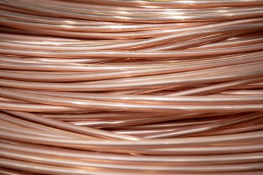 Parlak yüzeyi olan sarmalanmış bakır kabloların yakın çekimi, karmaşık örtüşen desenler, sıcak ışıklandırma..