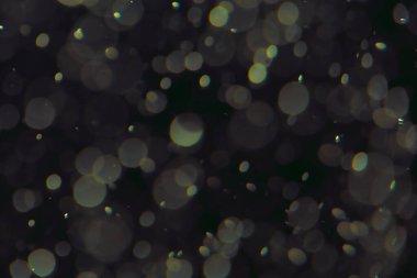 Koyu bir arkaplanda farklı boyut ve renklerde odaklanmış bokeh ışıkları.