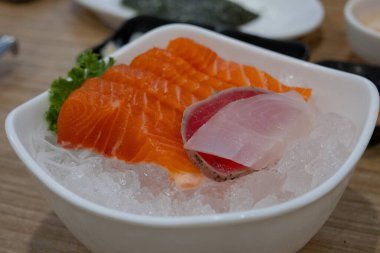 Ezilmiş buz yatağında servis edilen taze somon, ton balığı ve beyaz balıklı deniz ürünleri tabağının yakın çekimi..