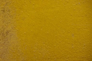 Kalıplı sarı beton yüzeyin yakın plan çekimi. Kaba ve biraz pürüzlü doku ve altın sarısındaki ince varyasyonlar, görsel olarak ilginç bir zemin oluşturur. Bazı ince yatay çizgiler görünür..