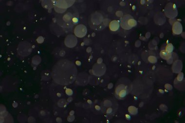 Koyu bir arkaplanda farklı boyut ve renklerde odaklanmış bokeh ışıkları.